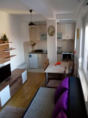 a living room and kitchen with a table and a purple couch at Apartman Mihajlovic in Soko Banja