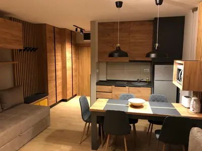 a kitchen and living room with a table and chairs at Apartmani A in Kopaonik