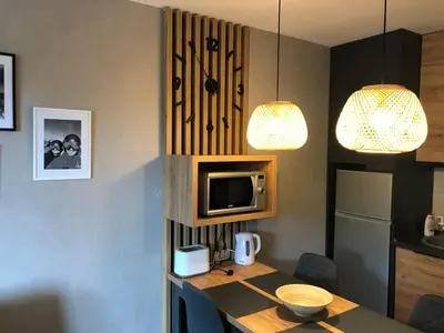 a kitchen with a table with a microwave and two lights at Apartmani A in Kopaonik