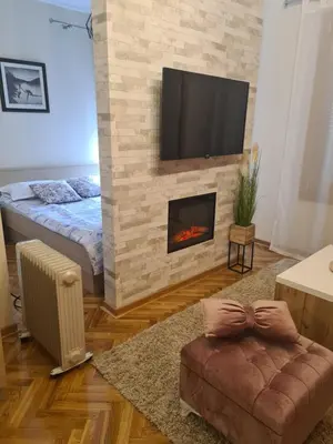 a living room with a fireplace and a tv on a brick wall at Happy Moments in Vrnjačka Banja