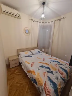 a bedroom with a bed with a comforter on it at Happy Moments in Vrnjačka Banja