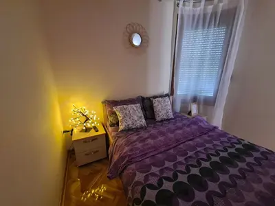 a bedroom with a purple bed and a window at Happy Moments in Vrnjačka Banja