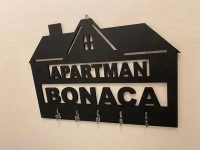 a black sign on a wall with a house at Apartman Bonaca in Niš