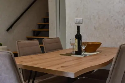 a wooden table with a bottle of wine and two glasses at STIV Apartmani in Lukovo