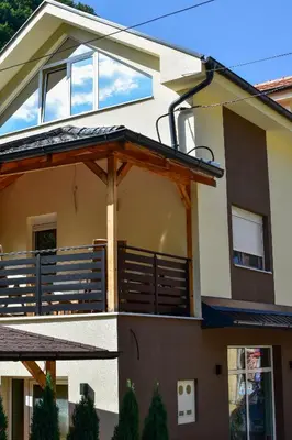 a house with a large deck on the side of it at STIV Apartmani in Lukovo