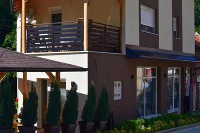 a house with a balcony and trees in front of it at STIV Apartmani in Lukovo