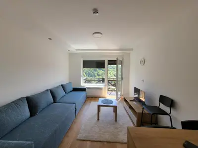 a living room with a blue couch and a table at Apartman Mela Kop 11 in Kopaonik