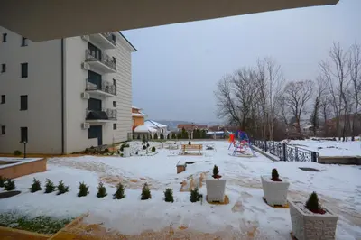 a courtyard covered in snow next to a building at Apartman Pašajlić in Vrnjačka Banja
