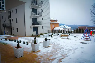 a courtyard with snow and potted plants in front of a building at Apartman Pašajlić in Vrnjačka Banja