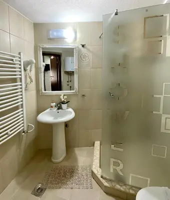 a bathroom with a sink and a shower with a mirror at STUDIO Vladana in Kruševac