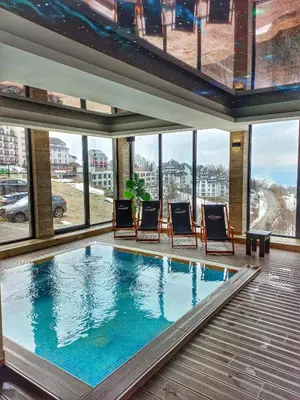 a swimming pool in a building with chairs and windows at Milmari Resort N56 Kopaonik wellnes&spa in Kopaonik