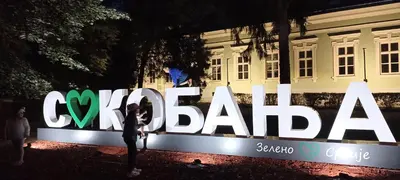 a person standing in front of a large sign in front of a building at Apartman Bane in Soko Banja