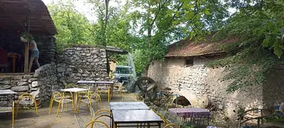 a patio with tables and chairs next to a stone building at Apartman Bane in Soko Banja