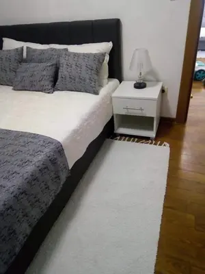 a bedroom with a bed and a night stand with a lamp at Pegaz114 in Vrnjačka Banja