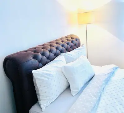 a bed with pillows on top of it with a lamp at Charme apartman in Kruševac