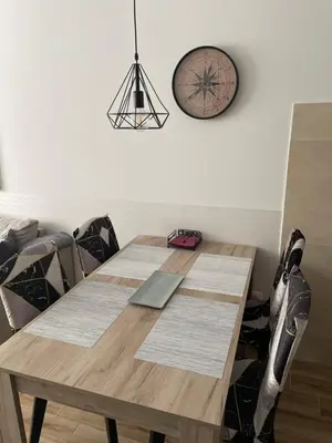 a wooden table with chairs and a clock on the wall at Apartments Dora in Kopaonik