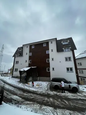 a car parked in front of a building in the snow at Apartments Dora in Kopaonik