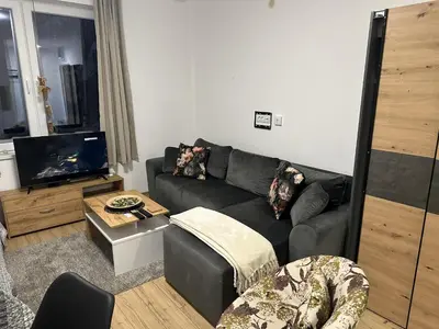 a living room with a black couch and a flat screen tv at Apartments Dora in Kopaonik