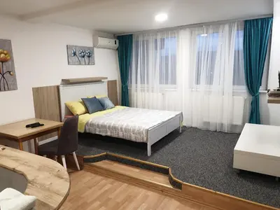 a bedroom with a bed and a table and a desk at City center apartment 2 in Niš