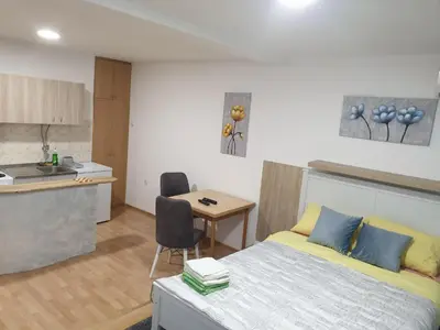 a bedroom with a bed and a table and a kitchen at City center apartment 2 in Niš