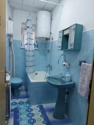 a blue bathroom with a sink and a toilet at Hills Apartment in Niš