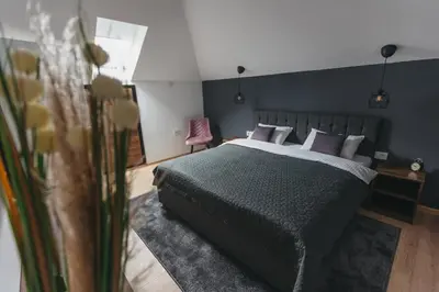 a bedroom with a large bed and a pink chair at City Centar House in Niš