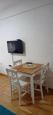 a wooden table with two chairs and a television at Visnja Aparmtani in Vrnjačka Banja