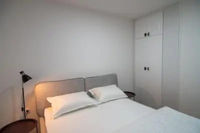 a bedroom with a bed with white sheets and a lamp at Visnja Aparmtani in Vrnjačka Banja