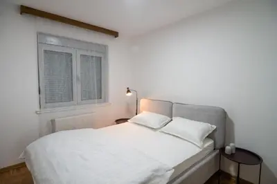 a white bed in a room with a window at Visnja Aparmtani in Vrnjačka Banja