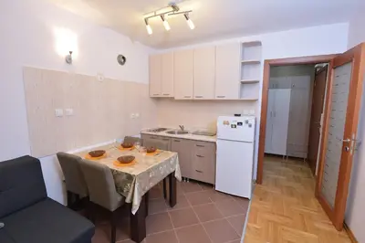 a kitchen with a table and a white refrigerator at Studio apartman Zvezdana Noć in Vrnjačka Banja