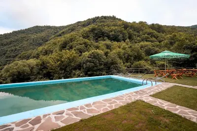 a swimming pool with a table and an umbrella at Jaćimov Konak in Pirot