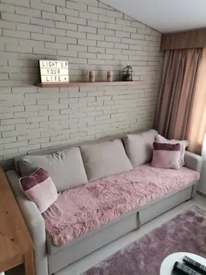 a couch in a room with a brick wall at Apartman N101, Milmari, Kopaonik in Kopaonik