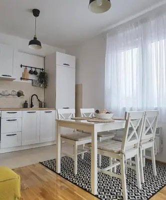 a kitchen with a white table and white chairs at Apartman LUMI in Vrnjačka Banja