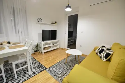 a living room with a yellow couch and a table at Apartman LUMI in Vrnjačka Banja