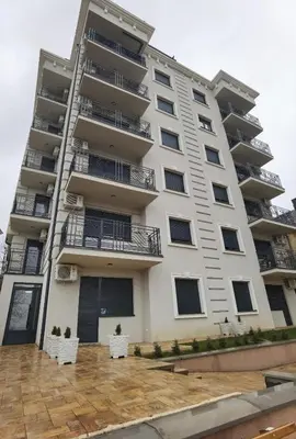 a tall building with white chairs in front of it at Apartman LUMI in Vrnjačka Banja