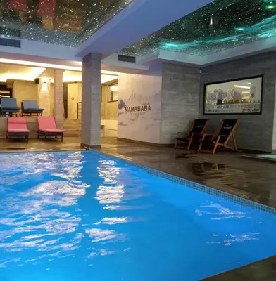 a large swimming pool in a hotel lobby with chairs at HUSKY Milmari in Kopaonik