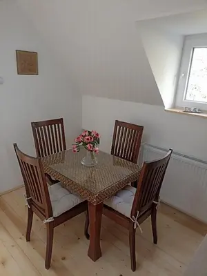 a dining room table with three chairs and flowers on it at Vila Gala in Kopaonik