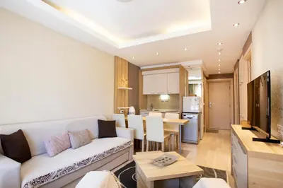 a living room with a white couch and a kitchen at kopaonik konaci centar lux apartman in Kopaonik