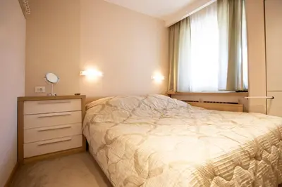 a bedroom with a bed and a dresser and a window at kopaonik konaci centar lux apartman in Kopaonik
