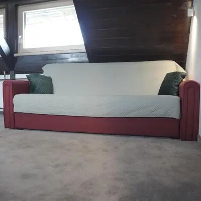a bed sitting in front of a window at Vučko apartmani Konaci in Kopaonik