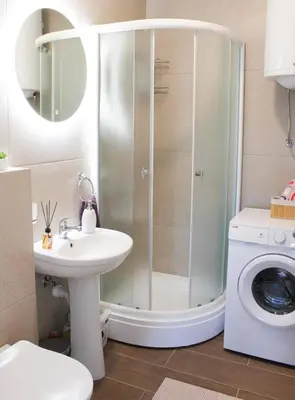 a bathroom with a shower and a sink and a washing machine at Apartment Atria II in Vrnjačka Banja