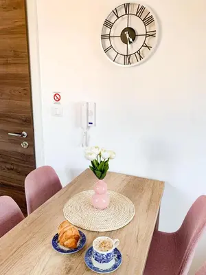 a table with a vase of flowers and a cup of coffee at Apartment Atria II in Vrnjačka Banja