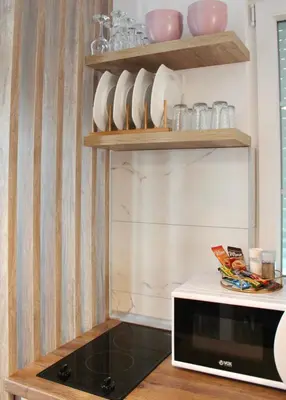 a kitchen with wooden shelves and a microwave at Apartment Atria II in Vrnjačka Banja
