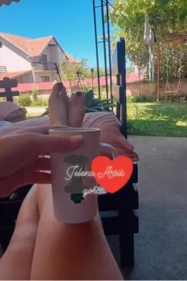 a person holding a coffee cup with their feet on a bed at Apartman ''Nena,, in Soko Banja