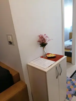 a small white cabinet with a vase of flowers on it at Apartman Centar 2 in Kruševac
