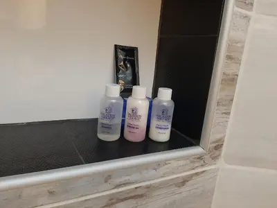three bottles of lotion sitting on a shelf in a bathroom at Apartman Centar 2 in Kruševac