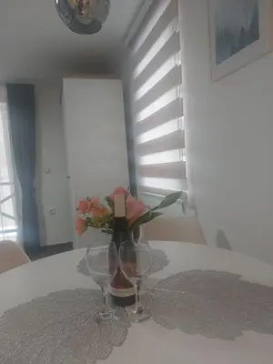 a table with two wine glasses and a vase with flowers at Apartman Milly in Kopaonik