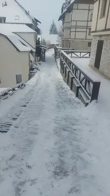 a snow covered street with a bridge and buildings at Apartman Milly in Kopaonik
