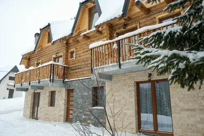 a log home with a deck in the snow at Drvena Kuca RUŽA in Kopaonik