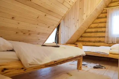 a log cabin bedroom with a bed and a window at Drvena Kuca RUŽA in Kopaonik